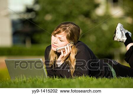 Stock Image - Young woman with laptop computer and cell phone - Vancouver, British Columbia, Canada. Fotosearch
