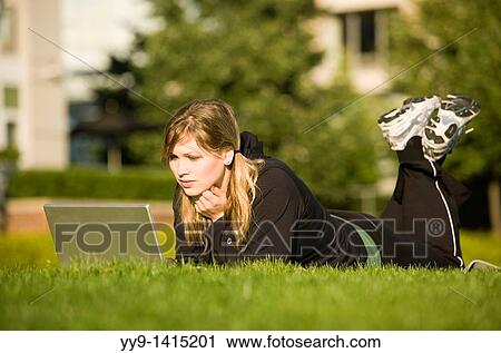 Stock Image - Young woman with laptop computer in grass - Vancouver, British Columbia, Canada. Fotosearch