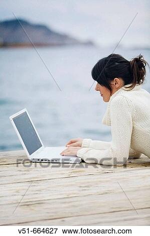 Stock Photo - Young woman with laptop on a bridge.. Fotosearch