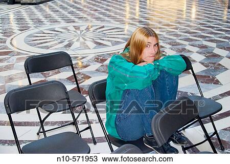 Young woman with long hair sitting on a chair in an office building lobby View Large Photo Image Stock Image - Young woman with long hair sitting on a chair in an office building lobby. Fotosearch