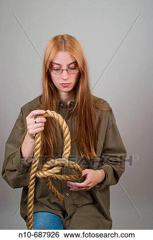 Young woman, with long red hair and glasses, making knots in a thick rope. View Large Photo Image Stock Photograph - Young woman, with long red hair and glasses, making knots in a thick rope.. Fotosearch