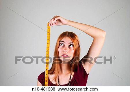 Young woman, with long red hair, using a tape measure View Large Photo Image Stock Photo - Young woman, with long red hair, using a tape measure. Fotosearch