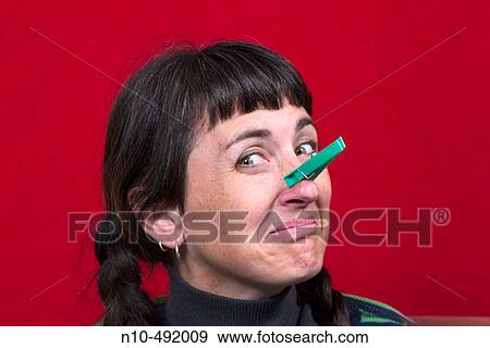 Stock Photo - Young woman with pigtails and a clothespin clamped to her nose. Fotosearch