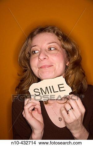 Young woman, with red hair, holding up a sign stating Smile"" View Large Photo Image Picture - Young woman, with red hair, holding up a sign stating Smile"". Fotosearch