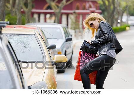 Stock Photograph - Young woman with shopping bags is looking for a car keys. Fotosearch
