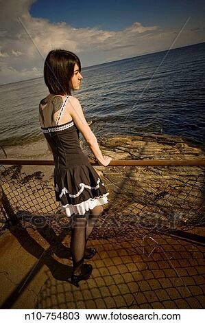 Young woman, with tattoos on her back, looking at the ocean. View Large Photo Image Stock Image - Young woman, with tattoos on her back, looking at the ocean.. Fotosearch