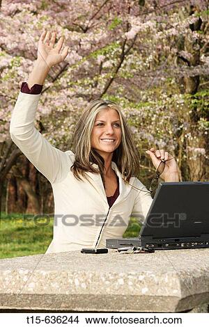 Young woman working in a park waving hello View Large Photo Image Picture - Young woman working in a park waving hello. Fotosearch