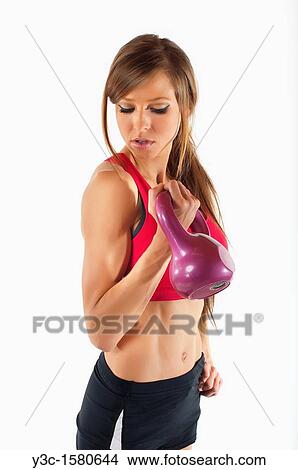 Young woman working out with dumbbells while watching her biceps View Large Photo Image Picture - Young woman working out with dumbbells while watching her biceps. Fotosearch