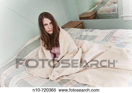 Young woman, wrapped in a blanket, sitting on her bed. View Large Photo Image Stock Photography - Young woman, wrapped in a blanket, sitting on her bed.. Fotosearch