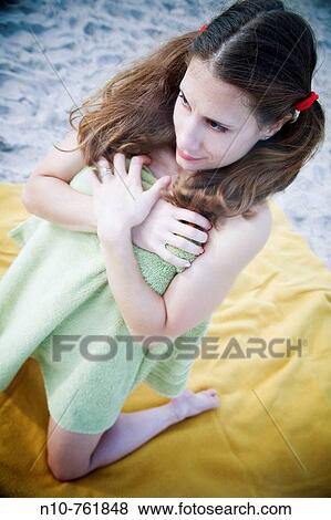 Young woman, wrapped in a towel, kneeling on a blanket at the beach View Large Photo Image Stock Photo - Young woman, wrapped in a towel, kneeling on a blanket at the beach. Fotosearch
