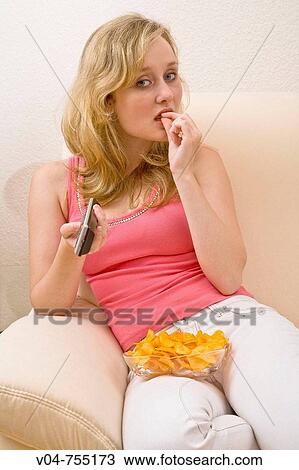 Young woman zapping and eating chips View Large Photo Image Stock Image - Young woman zapping and eating chips. Fotosearch