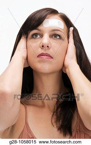Stock Photography - young womann with adhesive plaster on her forehead for a slight wound. Fotosearch