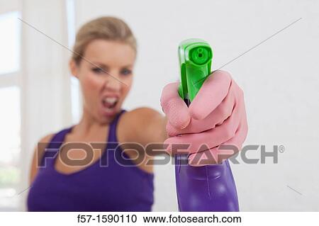 Stock Image - Young women aggresively cleaning her home. Fotosearch