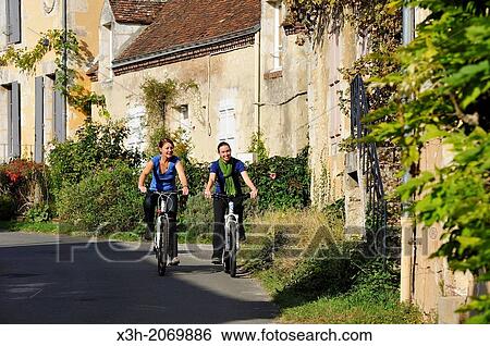 Stock Photograph - young women cycling in the village of Villeray, Commune of Condeau, Orne department, Lower Normandy region, France, Western Europe.. Fotosearch