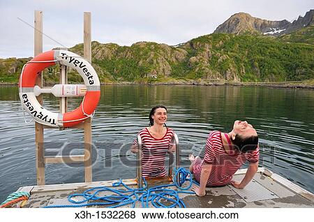 young women, dressed with an old-fashioned swimming costume, bathing into the icy water of the fjord, Hamn i Senja Hotel, Senja island, County of Troms, Norway, Northern Europe View Large Photo Image Stock Photo - young women, dressed with an old-fashioned swimming costume, bathing into the icy water of the fjord, Hamn i Senja Hotel, Senja island, County of Troms, Norway, Northern Europe. Fotosearch