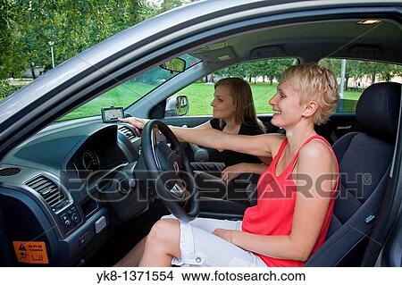 Picture - Young women in car on road trip using gps. Fotosearch