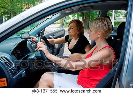 Stock Photography - Young women in car on road trip using gps. Fotosearch