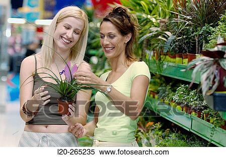 Stock Photography - Young women looking for house plants at shopping center. Fotosearch