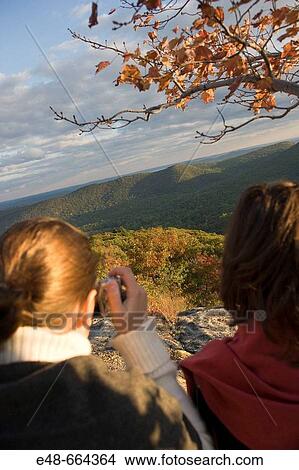 Young women outside taking photograph of landscape in fall View Large Photo Image Picture - Young women outside taking photograph of landscape in fall. Fotosearch
