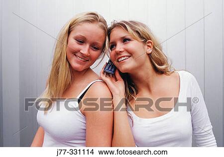 Young women sharing a phone conversation View Large Photo Image Picture - Young women sharing a phone conversation. Fotosearch