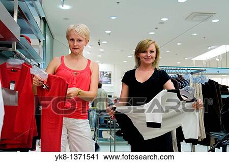 Young women shopping and comparing different clothes in store View Large Photo Image Stock Image - Young women shopping and comparing different clothes in store. Fotosearch