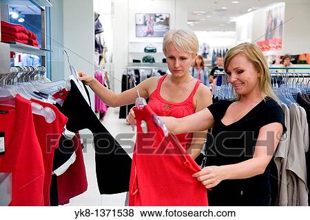 Young women shopping and comparing different clothes in store View Large Photo Image Stock Photo - Young women shopping and comparing different clothes in store. Fotosearch