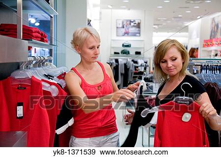 Young women shopping and comparing different clothes in store View Large Photo Image Stock Photo - Young women shopping and comparing different clothes in store. Fotosearch