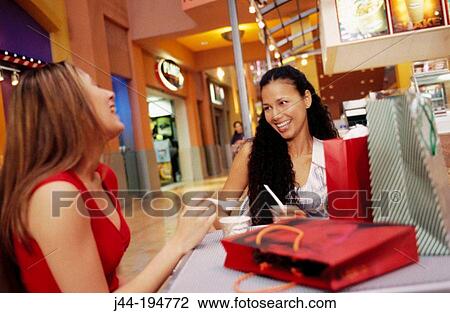 Young women sitting in a caf? with shopping bags, eating ice cream at the mall View Large Photo Image Stock Image - Young women sitting in a caf? with shopping bags, eating ice cream at the mall. Fotosearch