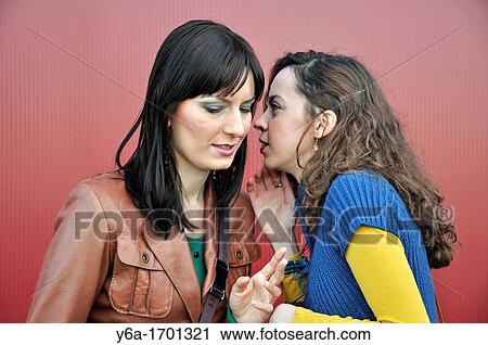 Young women whispering in friend ear outdoors View Large Photo Image Stock Image - Young women whispering in friend ear outdoors. Fotosearch