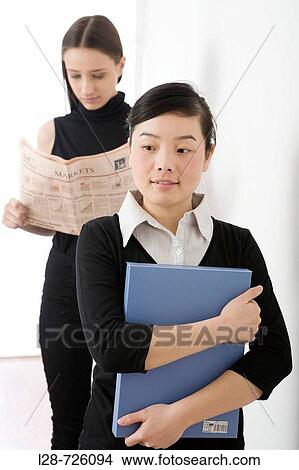 Young women with newspaper and file View Large Photo Image Picture - Young women with newspaper and file. Fotosearch