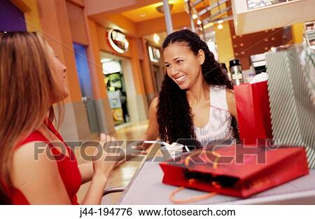 Young women with shopping baks, eating ice cream at the mall View Large Photo Image Stock Photograph - Young women with shopping baks, eating ice cream at the mall. Fotosearch