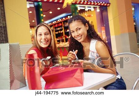 Young women with shopping baks, eating ice cream at the mall View Large Photo Image Stock Photography - Young women with shopping baks, eating ice cream at the mall. Fotosearch