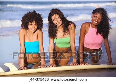 Young women with surfboard at the beach smiling View Large Photo Image Stock Photograph - Young women with surfboard at the beach smiling. Fotosearch