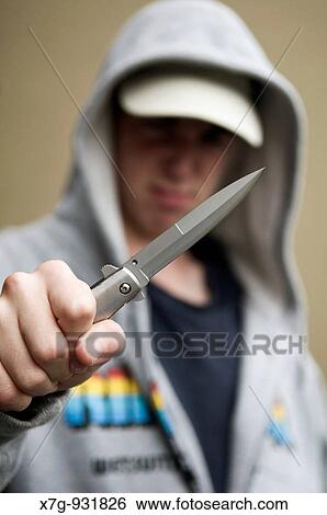 Stock Photograph - Youth in hoody brandishing flick knife. Fotosearch