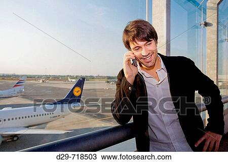 Stock Image - Yung man at the airport talking cell phone. Fotosearch
