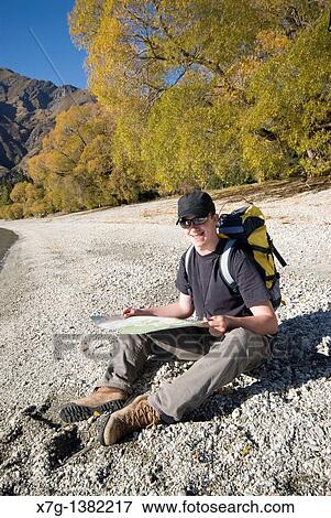 Stock Photo - YYoung hiker reading a map at Glendhu Bay on the shores of Lake Wanaka, South Island of New Zealand. Fotosearch