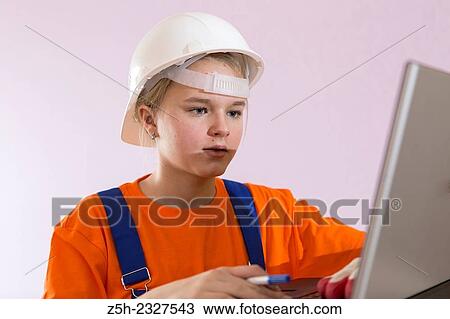 Stock Image - Beautiful girl-builder with a computer.. Fotosearch