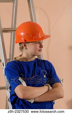 Stock Image - Beautiful girl-builder with a ladder.. Fotosearch