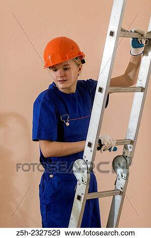 Stock Photo - Beautiful girl-builder with a ladder.. Fotosearch