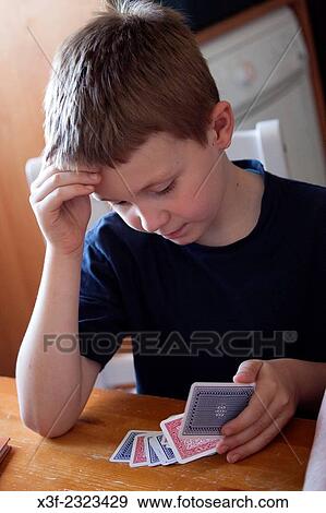 Boy age 8 concentrating while playing a game of cards. Lodz Central Poland. View Large Photo Image Stock Photo - Boy age 8 concentrating while playing a game of cards. Lodz Central Poland.. Fotosearch
