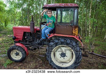 Boy age 8 waving from doorway of small Polish farm tractor. Zawady Central Poland. View Large Photo Image Stock Photo - Boy age 8 waving from doorway of small Polish farm tractor. Zawady Central Poland.. Fotosearch