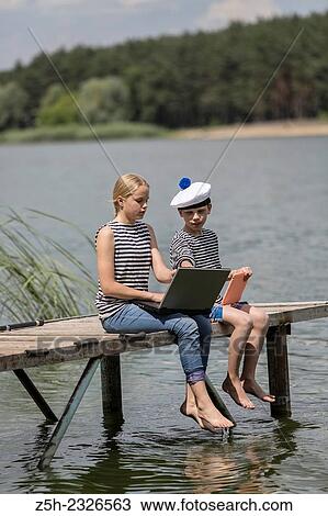 Boy and girl of twelve years in a sailor uniform with a laptop on the dock. View Large Photo Image Stock Image - Boy and girl of twelve years in a sailor uniform with a laptop on the dock.. Fotosearch