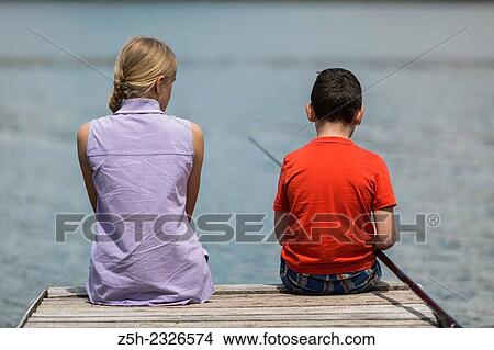 Picture - Boy and girl of twelve years on the pond fish udyat.. Fotosearch