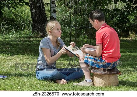 Stock Image - Boy and girl twelve years reading books on nature.. Fotosearch