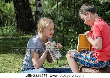 Stock Image - Boy and girl twelve years reading books on nature.. Fotosearch