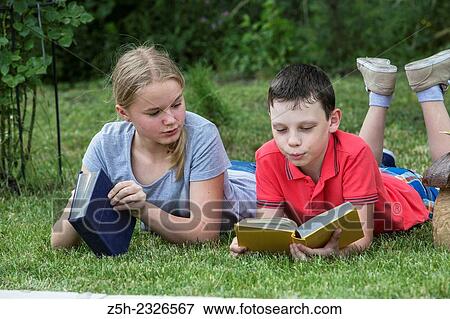 Stock Photo - Boy and girl twelve years reading books on nature.. Fotosearch
