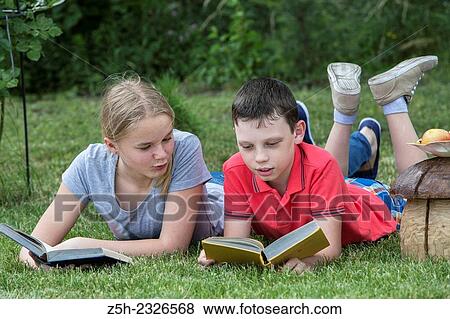 Stock Photo - Boy and girl twelve years reading books on nature.. Fotosearch