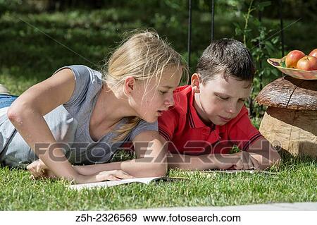 Stock Photo - Boy and girl twelve years reading books on nature.. Fotosearch