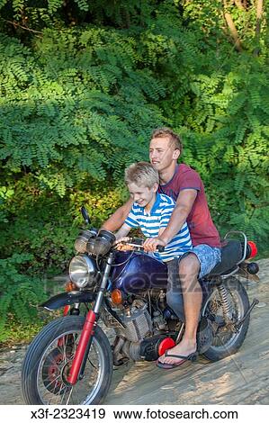 Boy riding on a Polish teens motorcycle traveling over a graveled country road age 18 and 10. Zawady Central Poland. View Large Photo Image Stock Photo - Boy riding on a Polish teens motorcycle traveling over a graveled country road age 18 and 10. Zawady Central Poland.. Fotosearch