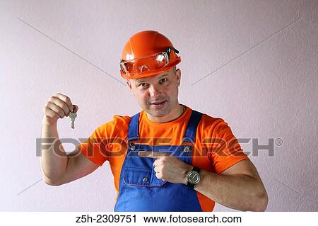 Stock Image - Builder shows the keys to the apartment, built by him.. Fotosearch